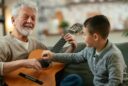 grandfather teaching his grandson to play guitar
