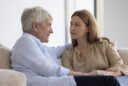 A senior father and his adult daughter share a thoughtful conversation speaking with care and honesty.