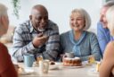 Older adults sharing laughter around a table — symbolizing rebuilding community in the second half of life.