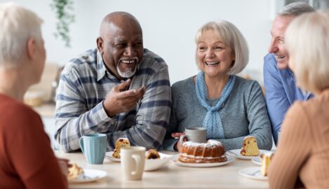 Older adults sharing laughter around a table — symbolizing rebuilding community in the second half of life.