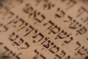 Close-up of Hebrew script with small crown-like markings above certain letters (tagin) in Torah writing